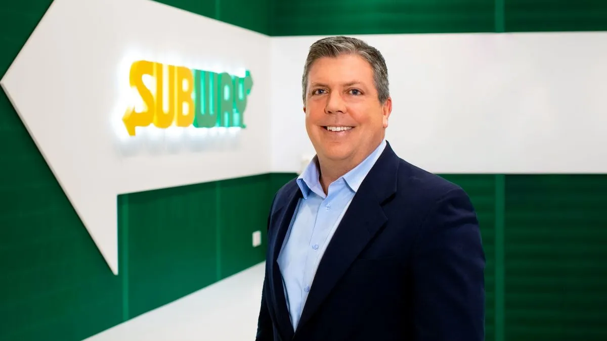 An image of Jeff Shepherd, Subway CFO, in front of a green and white Subway logo