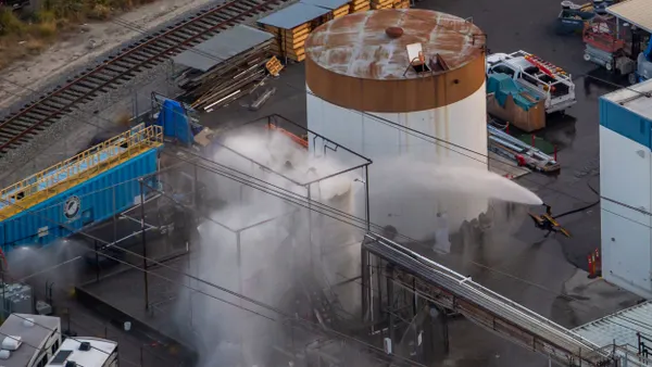 A device releasing a large spray of water onto a tank emitting smoke.