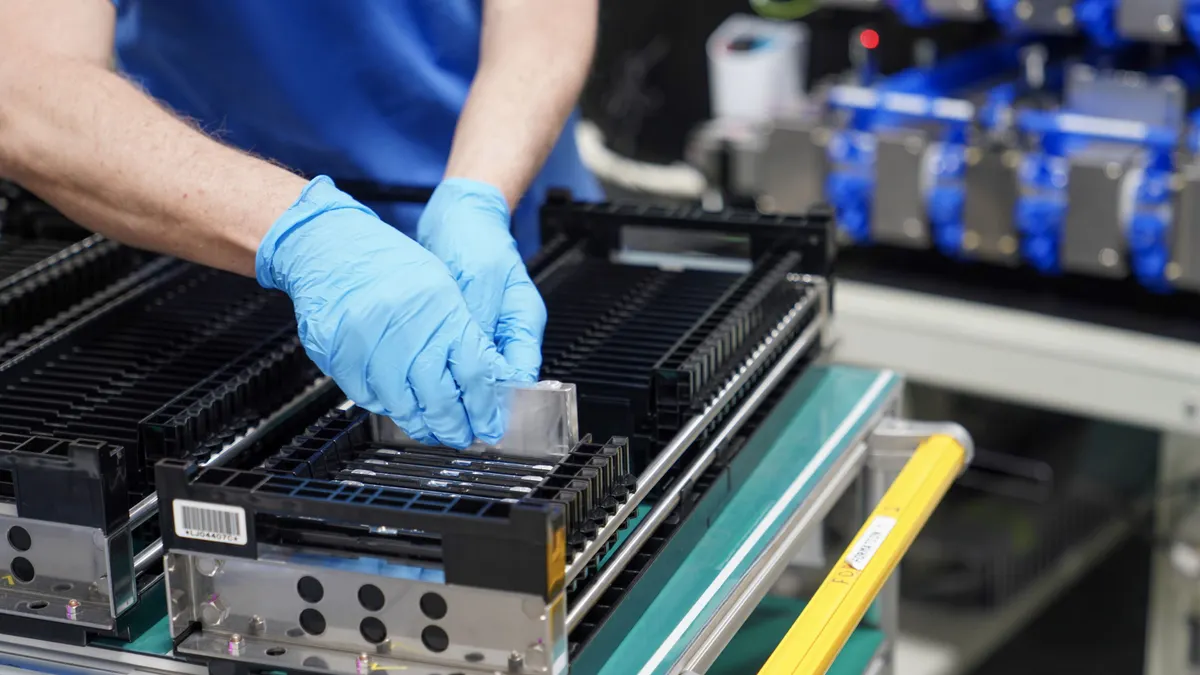 A person wearing gloves installing a device into an electric vehicle battery.