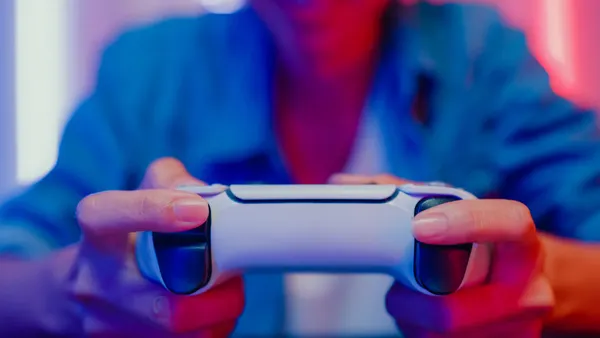 Close up of young Asian woman playing video game console in neon lights living room at home.