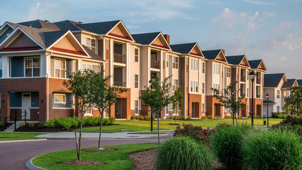 Three-story apartments with trees and a road in the foreground.