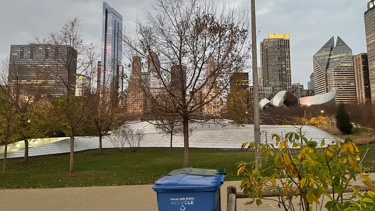 Blue recycling bin in a park, with Chicago skyline in background