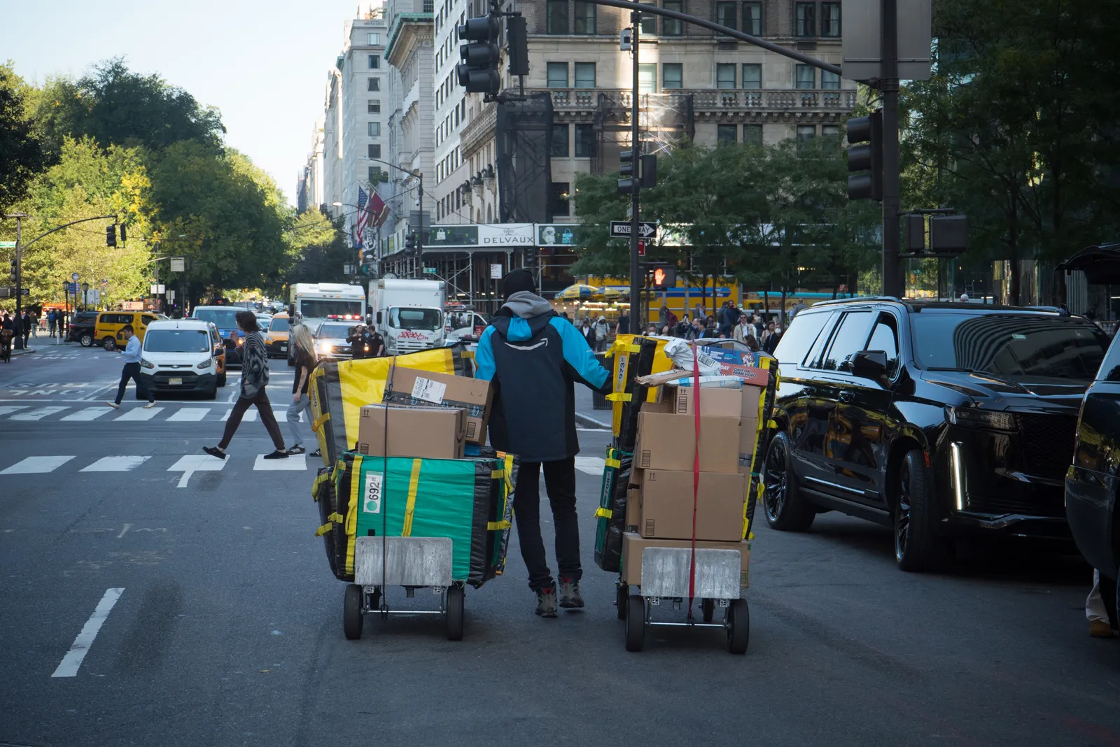 A person moves a cart of packages on a street.