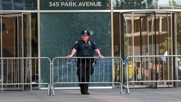 A New York Police Department (NYPD) officer stands in front of a bullet-shattered window at the 345 Park Avenue building.