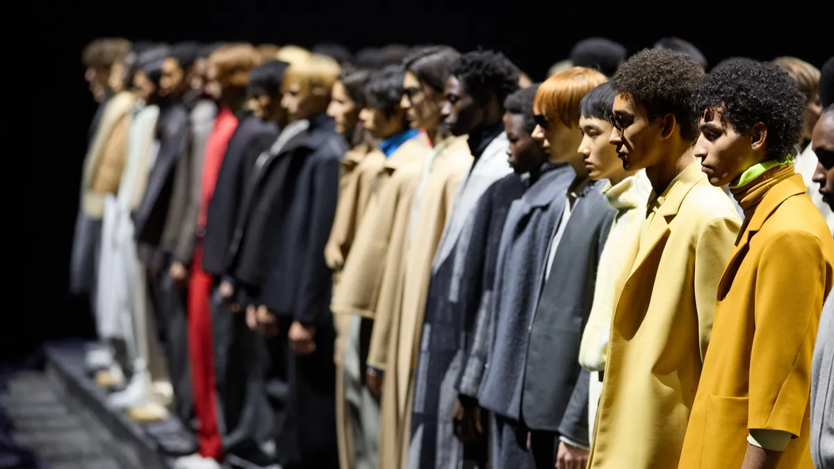 Models line the runway wearing colorful suits during a Zegna fashion show.