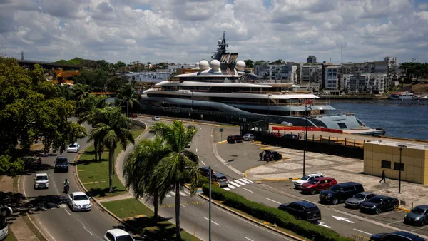 A large yacht sits at a dock in a port.