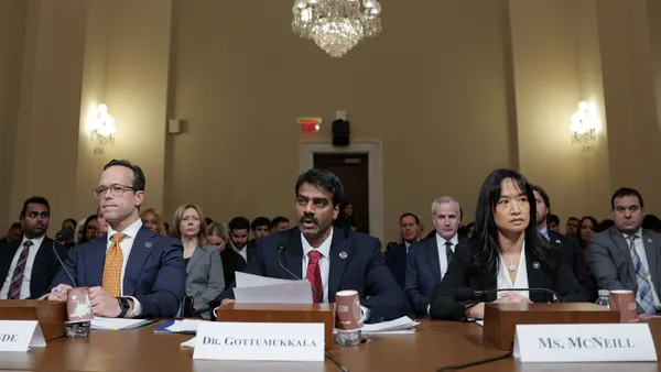Three people sit at a table in a congressional hearing room