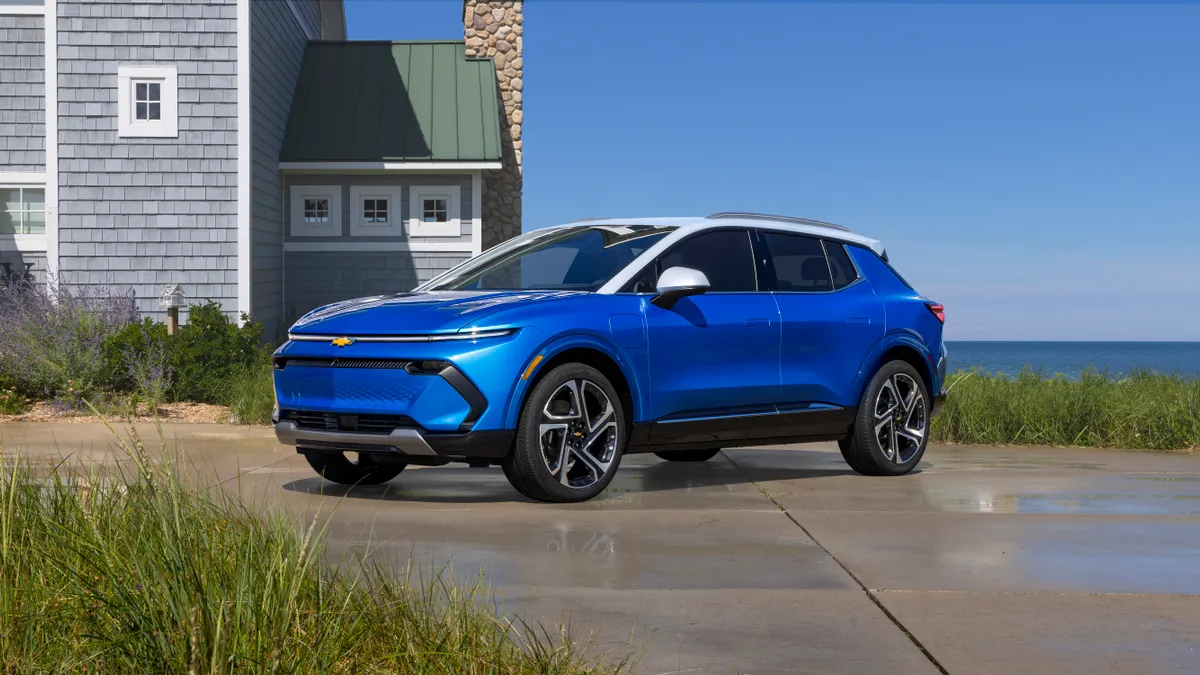 The 2024 Chevrolet Equinox EV 3LT in Riptide Blue parked beside a lakeside home.