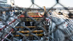 Looking at an empty construction site through a chain-link fence.