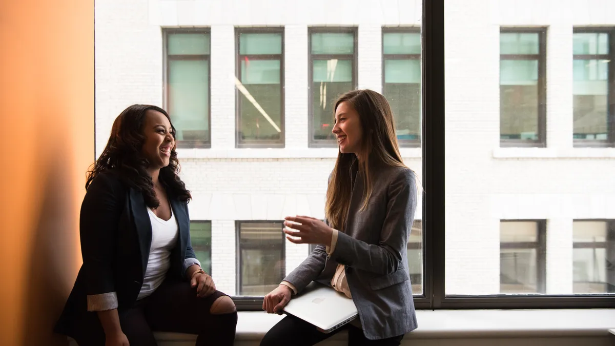 Two feminine-presenting people are talking in an office