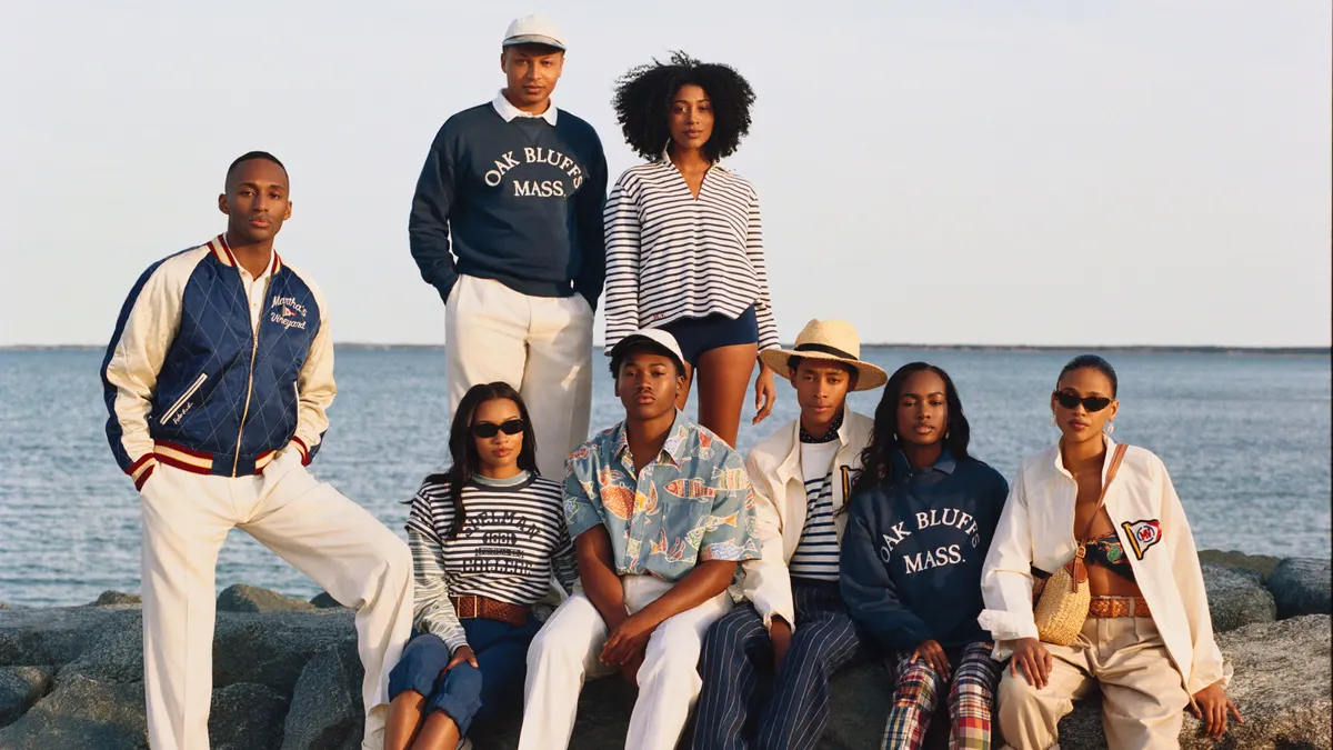 Eight people pose on a shoreline wearing clothing with Oak Bluffs logos.
