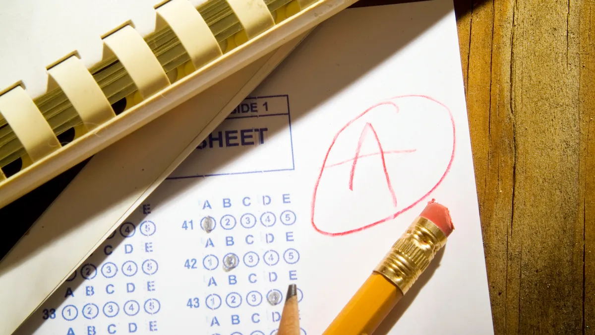 A paper with bubble test answers and a "A" written in the upper right hand corner lays on a desk with notebooks