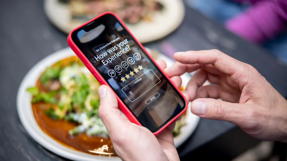 Close-up on a man rating his experience at a restaurant using an app on a cell phone.