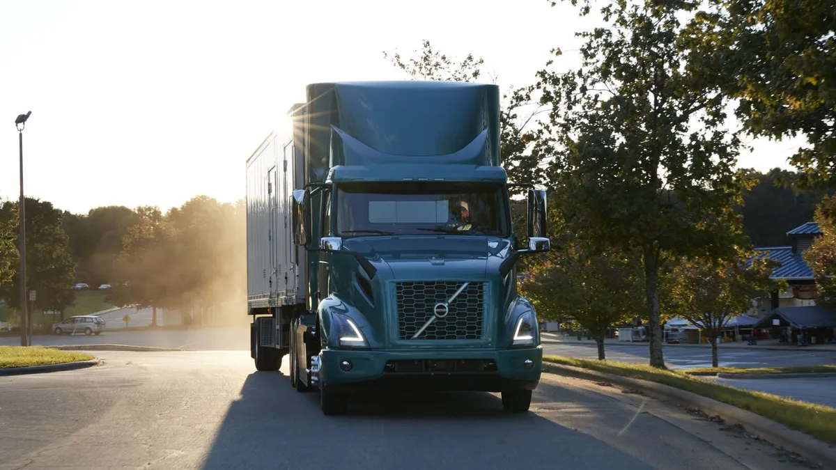 A Volvo VNR Electric truck at the American Trucking Associations' Management Conference & Exhibition with sunlight along the trailer.