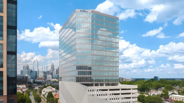 A multi-story glass office building is shown with the Charlotte skyline in the background.