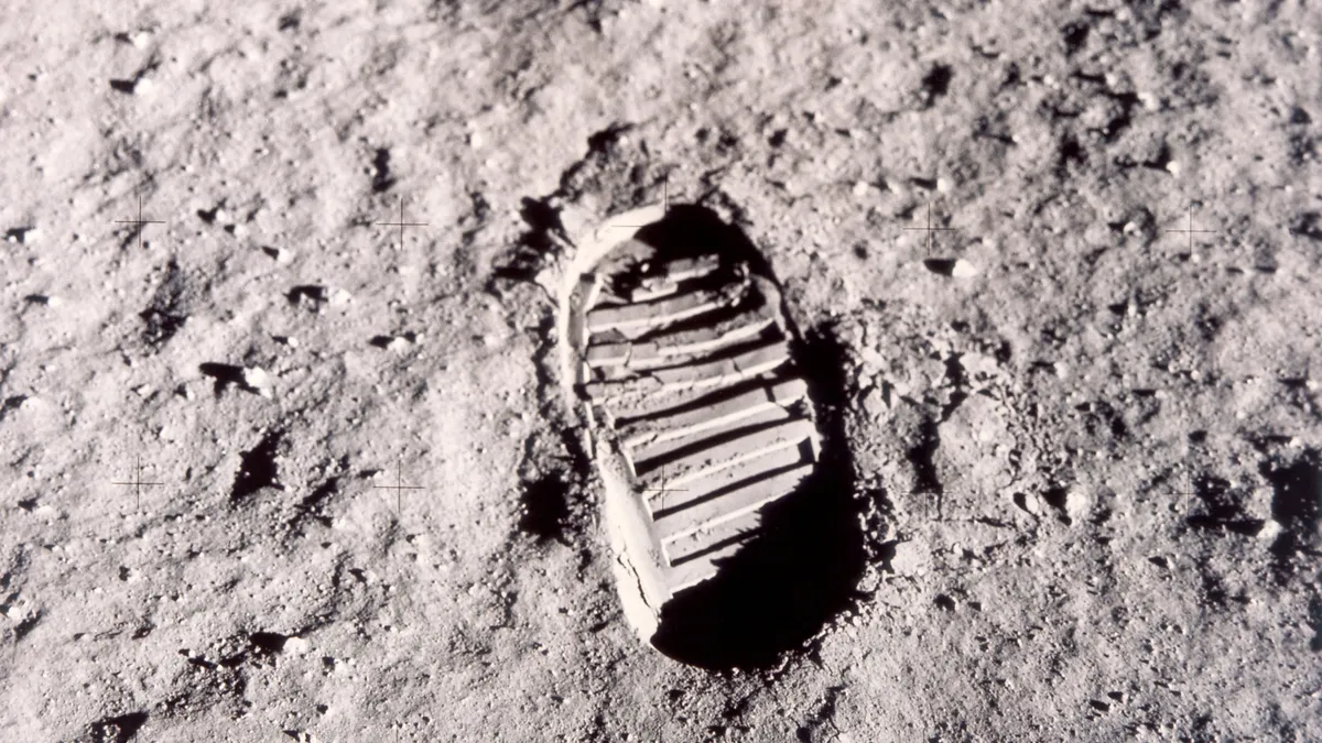 A footprint on the moon from an astronaut. There is an indent and a large bootprint.