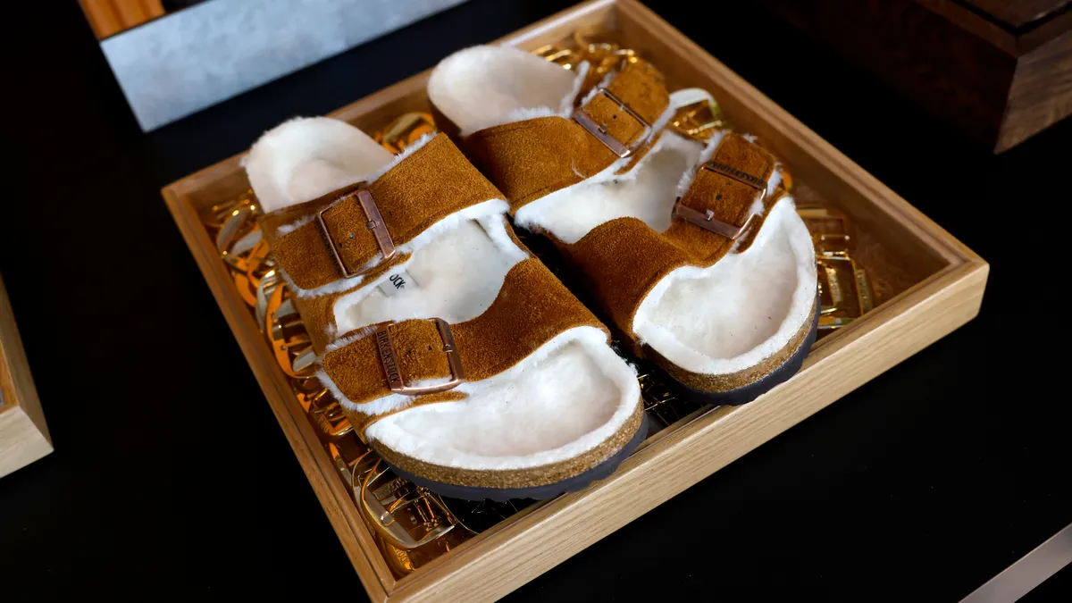 A pair of fur-lined Birkenstocks are pictured in a wooden box display.