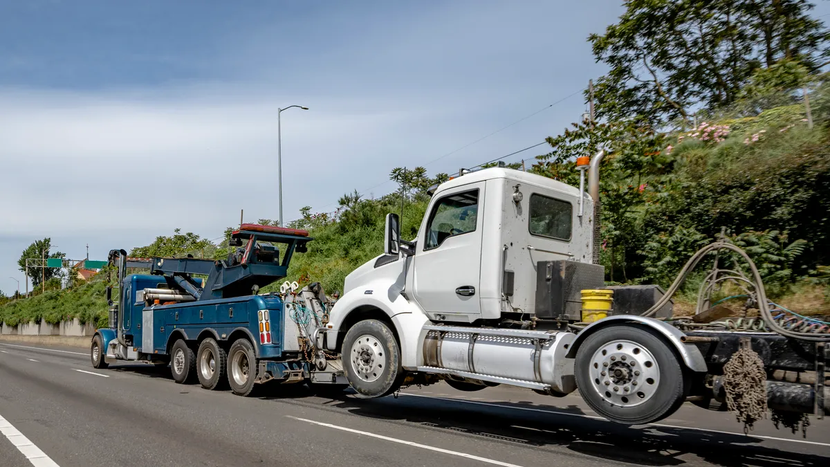 A tow truck pulls a broken-down semi truck.