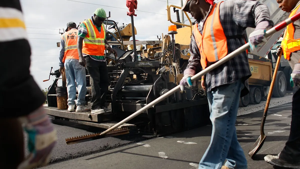 Construction workers in reflective vests work on building a road.