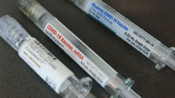 Boxes of COVID-19 vaccines from Pfizer and Moderna sit side by side.