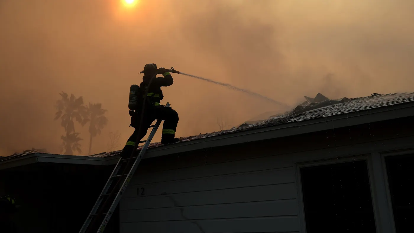 A firefighter sprays water on a burning home