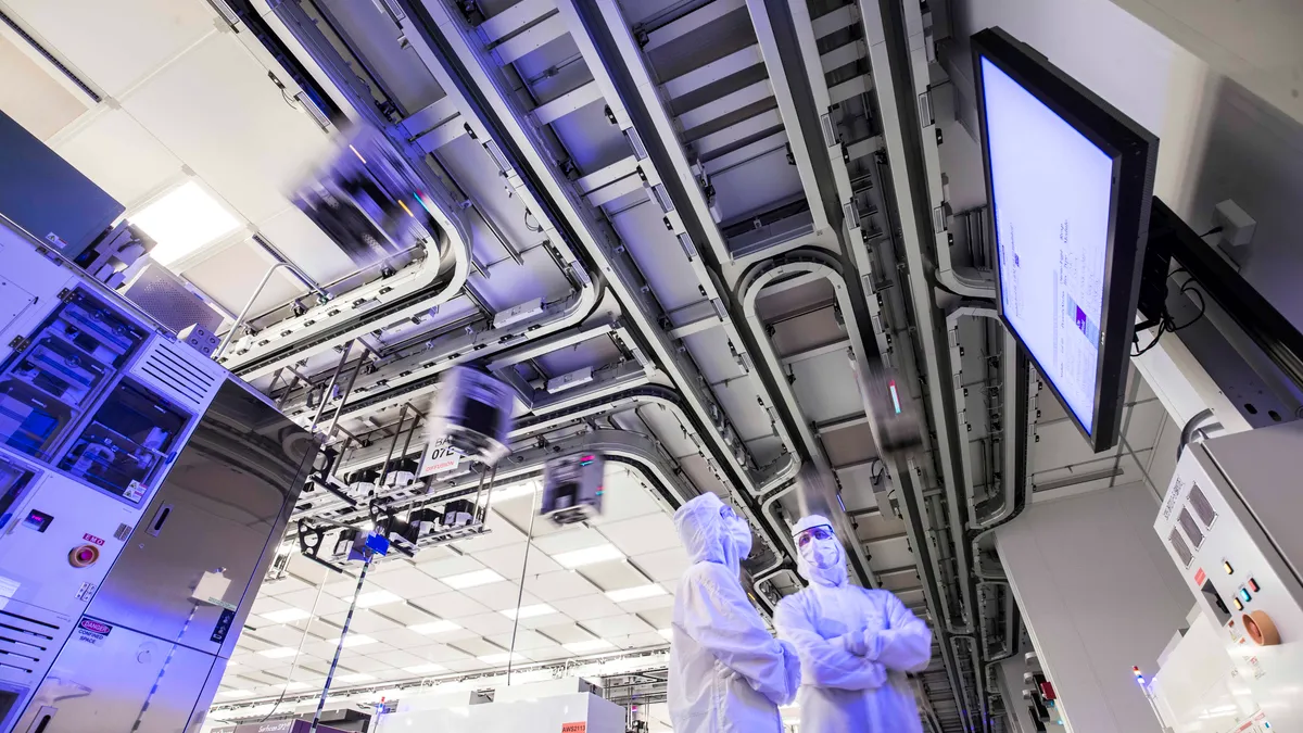 GlobalFoundries employees stand in a clean room inside a fabrication plant.