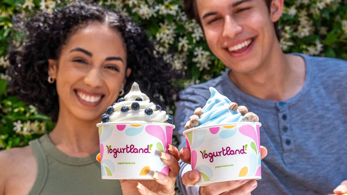 An image of a man and a woman holding up cups from Yogurtland.