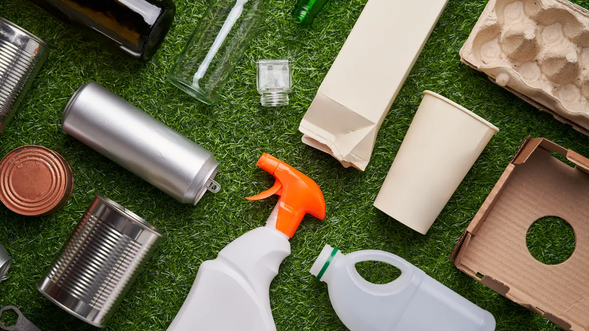 A variety of paper, plastic, glass and metal packaging on green artificial turf.