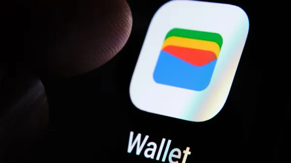 Close-up of a smartphone screen displaying the Google Wallet app interface, with a fingertip hovering above it, indicating user interaction.