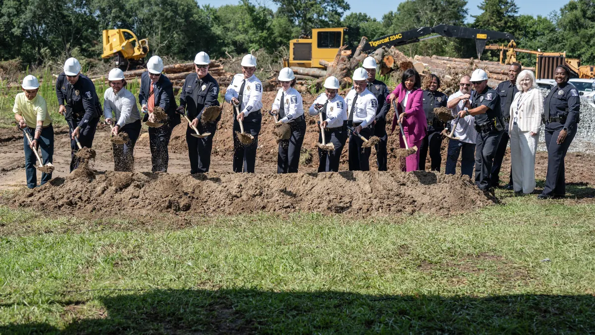A line of people, including several police officers, with shovels