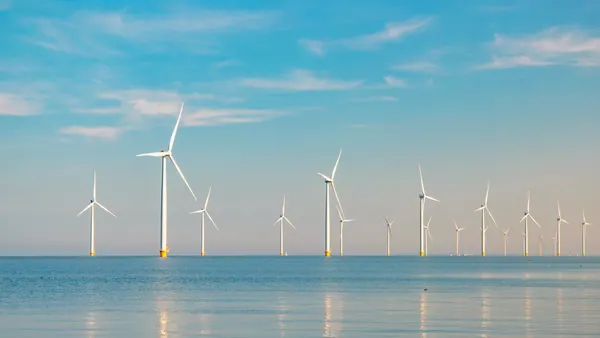 Wind turbines in the ocean against a blue sky
