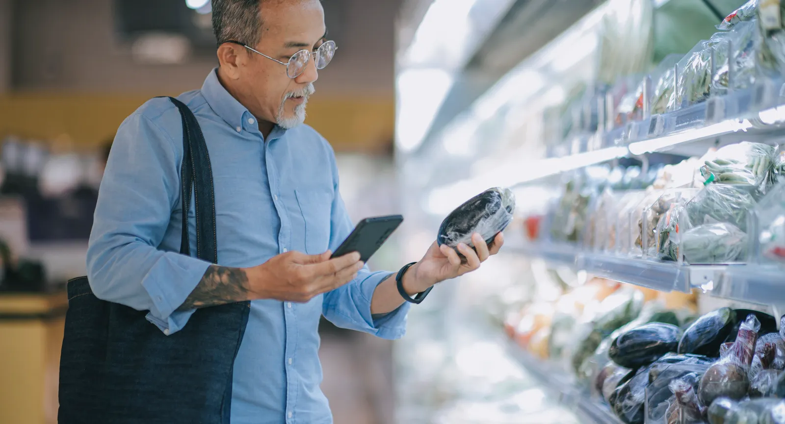 Person shopping with phone in the produce aisle at a grocery store