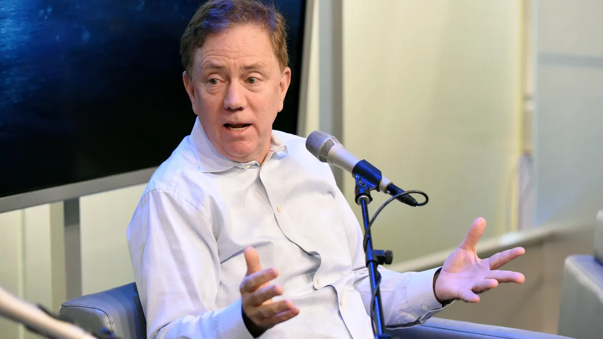 Ned Lamont speaks at a microphone during a podcast taping.