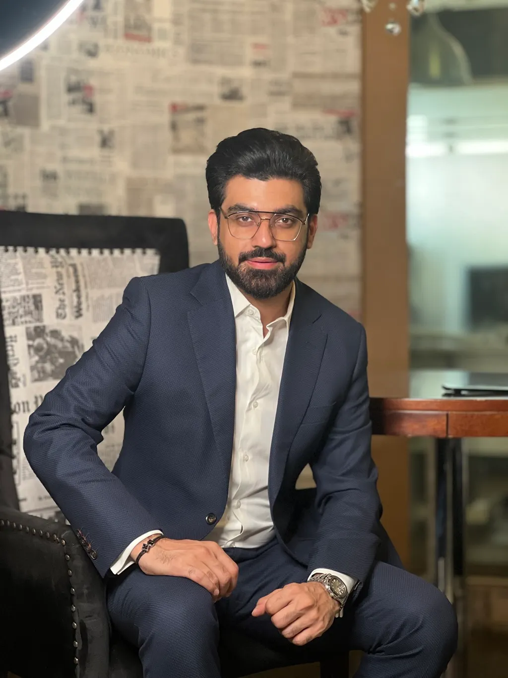 A photo of a person in a suit sitting in a chair.