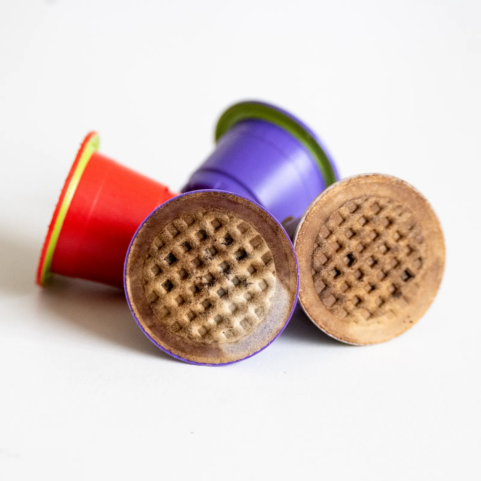 Four purple and red coffee pod capsules with lids.