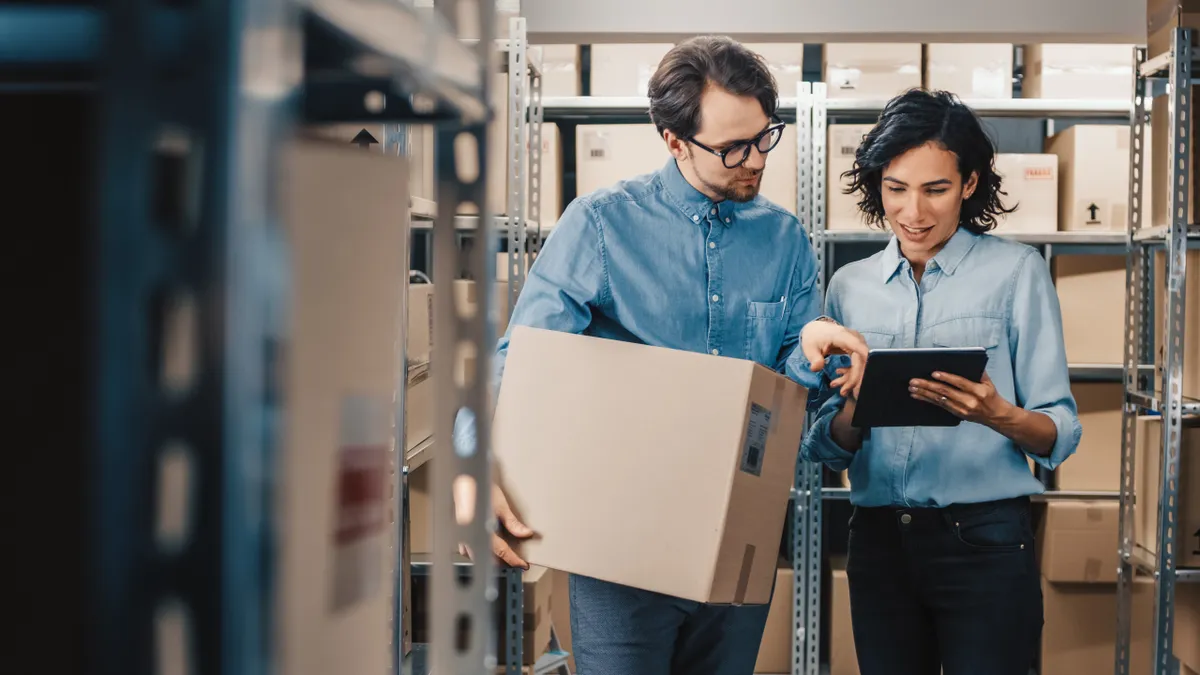 Employees in a warehouse looking at a tablet.