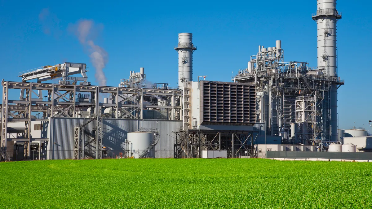 Natural gas fired turbine power plant with it's cooling towers rising into a blue sky.