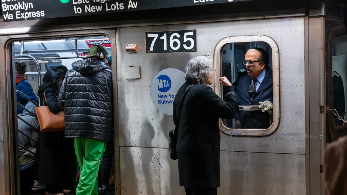 A conductor talks to a rider at a Manhattan subway station.