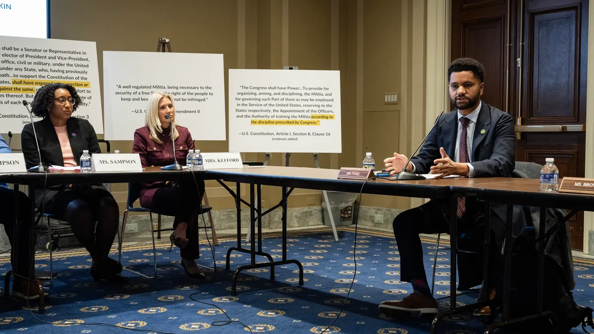 Rep. Maxwell Frost is seated at a table next to Kelly Sampson (L) and Michelle Kefford (C)