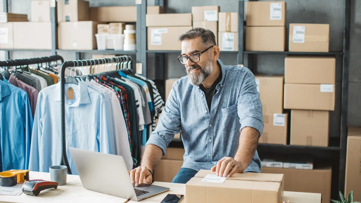 Mature man at online shop. He is owner of small online shop. Receiving orders and packing boxes for delivery.