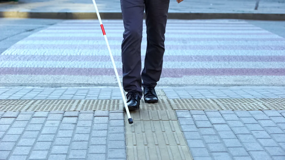 A visually impaired man uses tactile tiles to navigate the city.