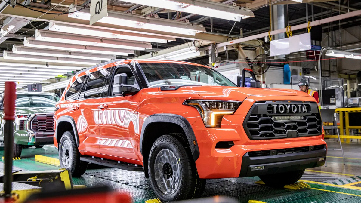 A reddish-orange SUV on a production line in a factory.