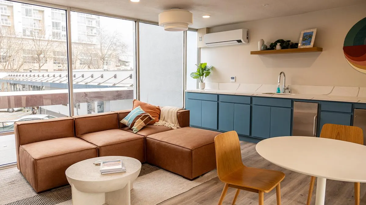 A room with tables, couches, and a kitchen area.