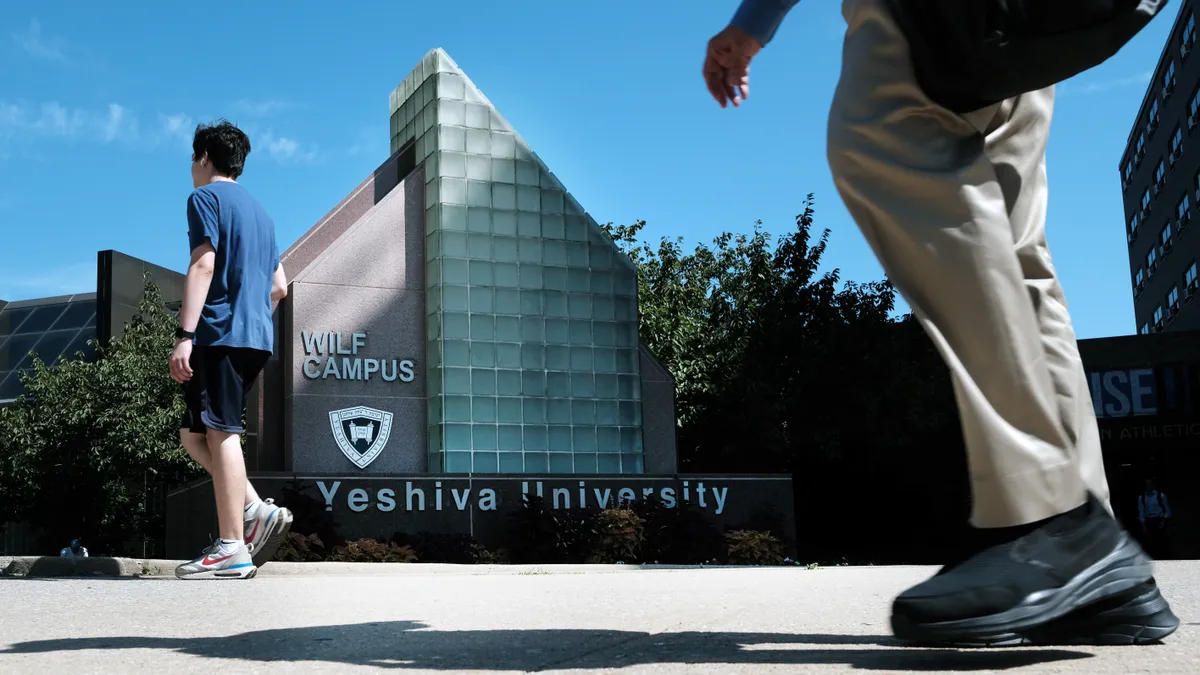 People walk by a Yeshiva University sign.