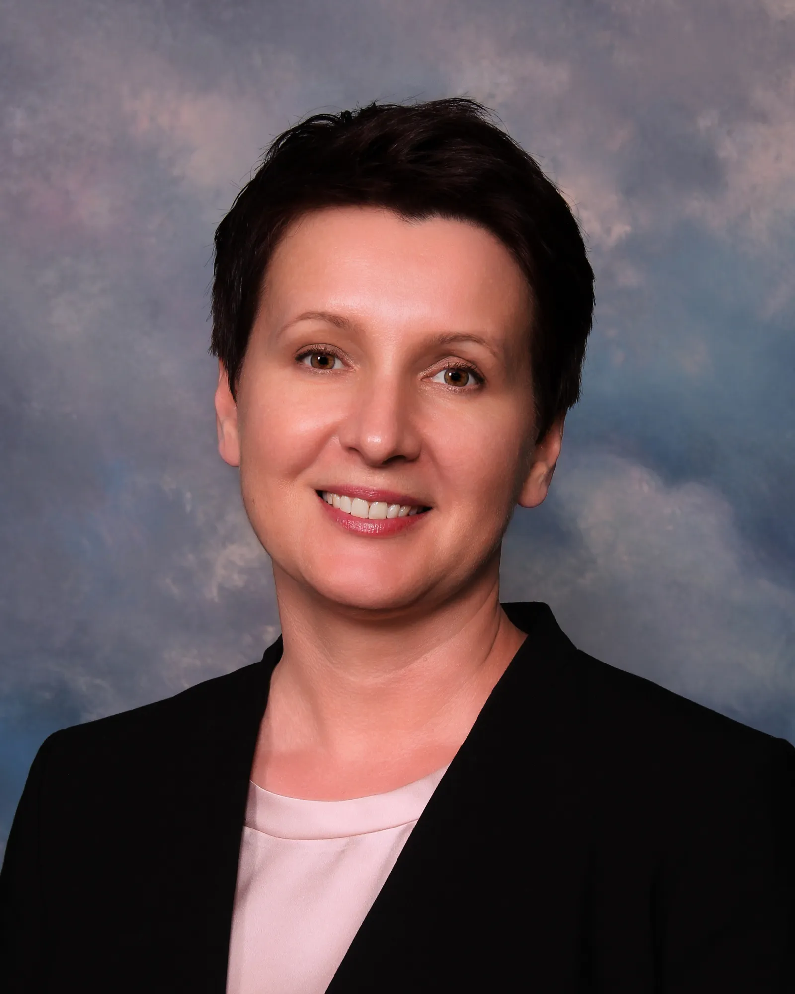 A headshot of a woman with a pixie cut in professional attire.