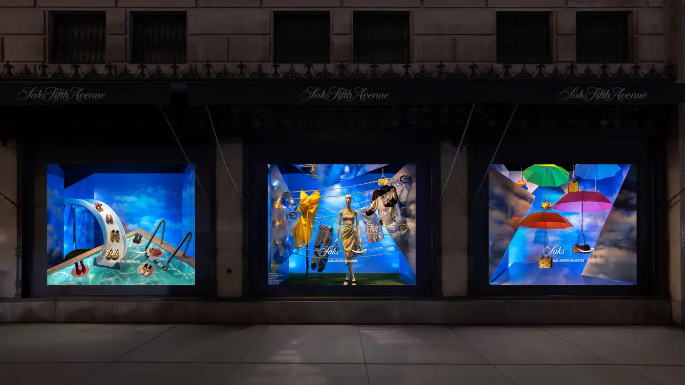 Windows in the Saks Fifth Avenue New York flagship store feature promotional staging of luxury fashion with logos from Amazon.