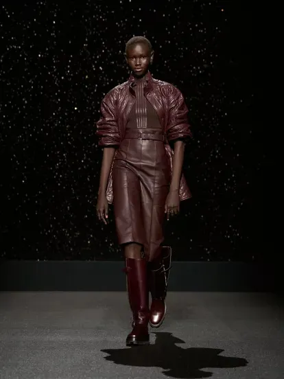 A model wears brown leather on a runway.