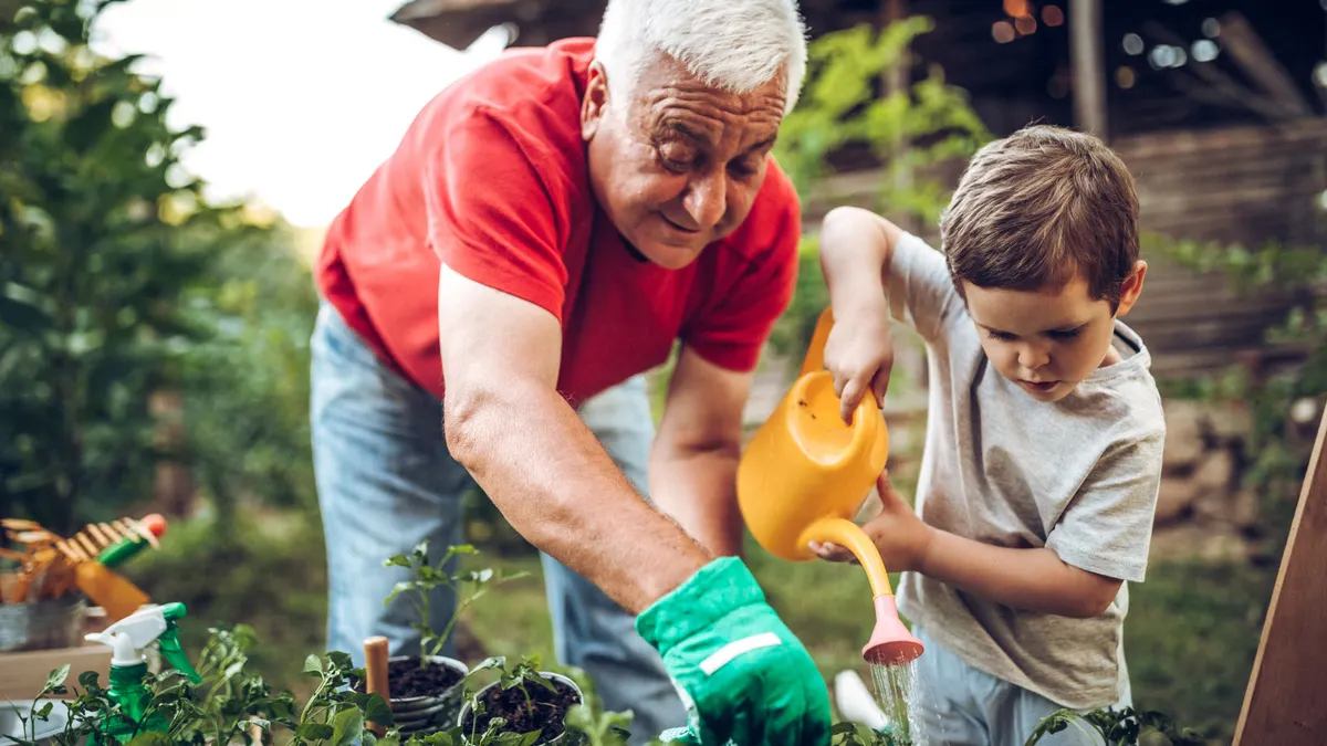 Grandfather and grandson playing in backyard with gardening tools