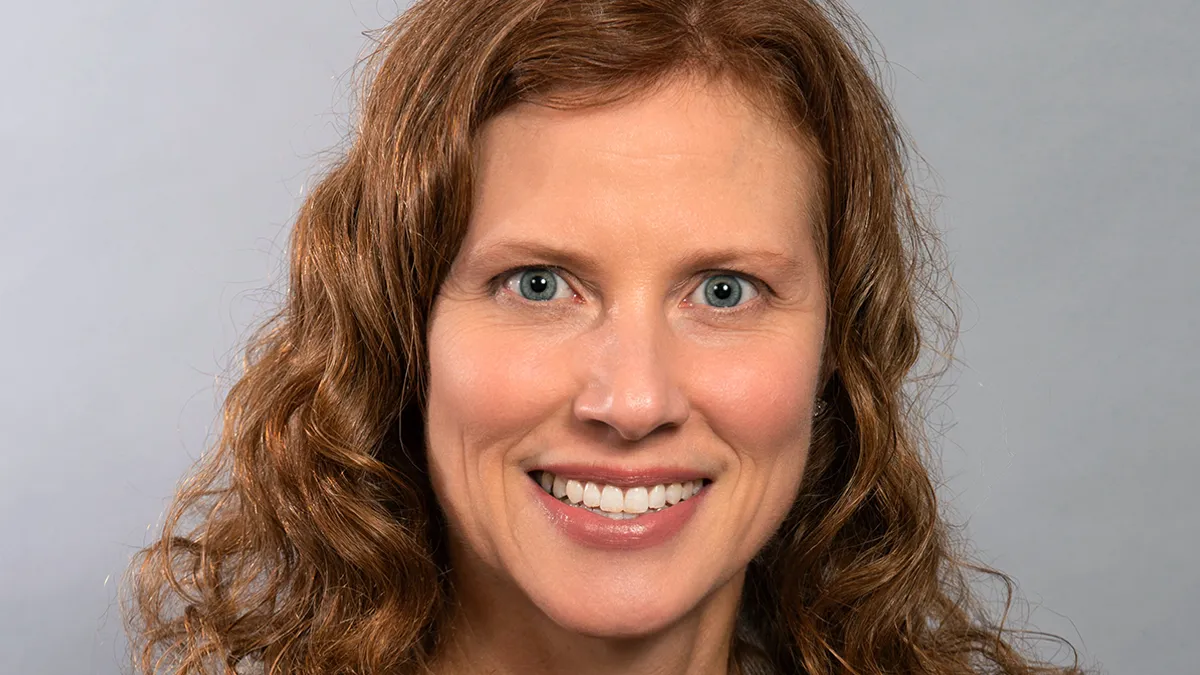 An image of a curly haired woman amid a gray background.