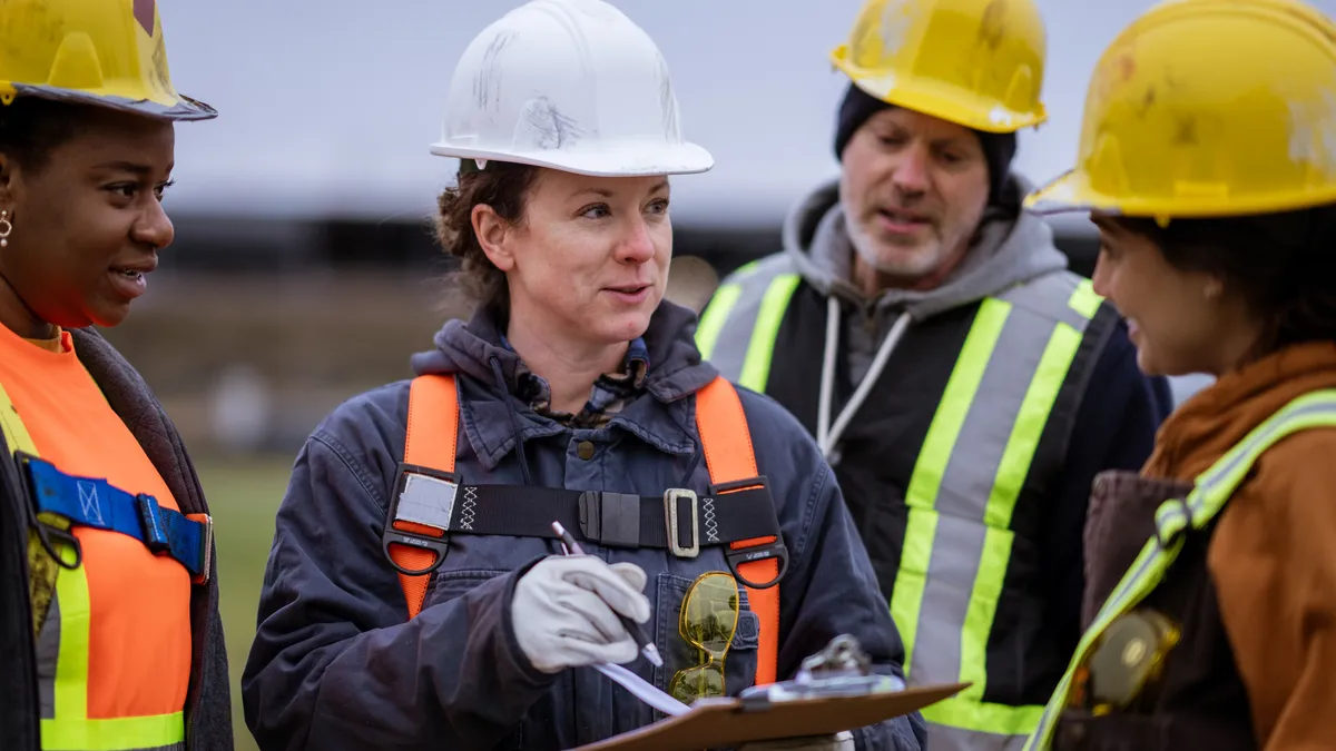 A group of people in construction equipment talking on a jobsite.